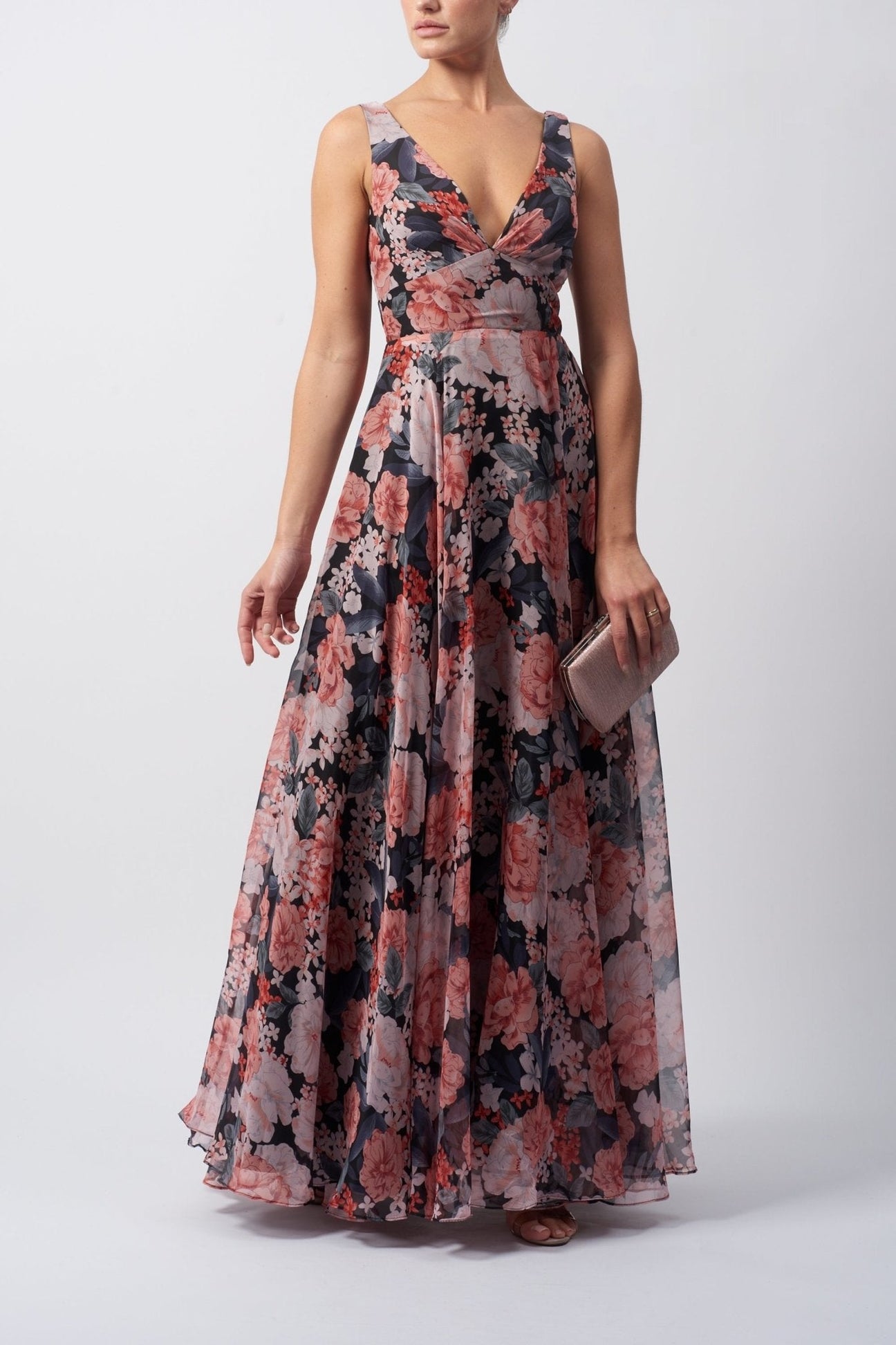 Model wearing a black floral printed V-neck chiffon dress with a full skirt and thick straps from Mascara London.